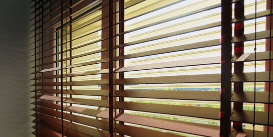 Protección solar formada por dos persianas, una primera en el exterior de lamas regulables y segunda interior de lamas de madera.